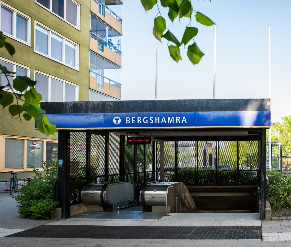 Tunnelbanenedgång i Bergshamra intill grönt lägenhetshus.