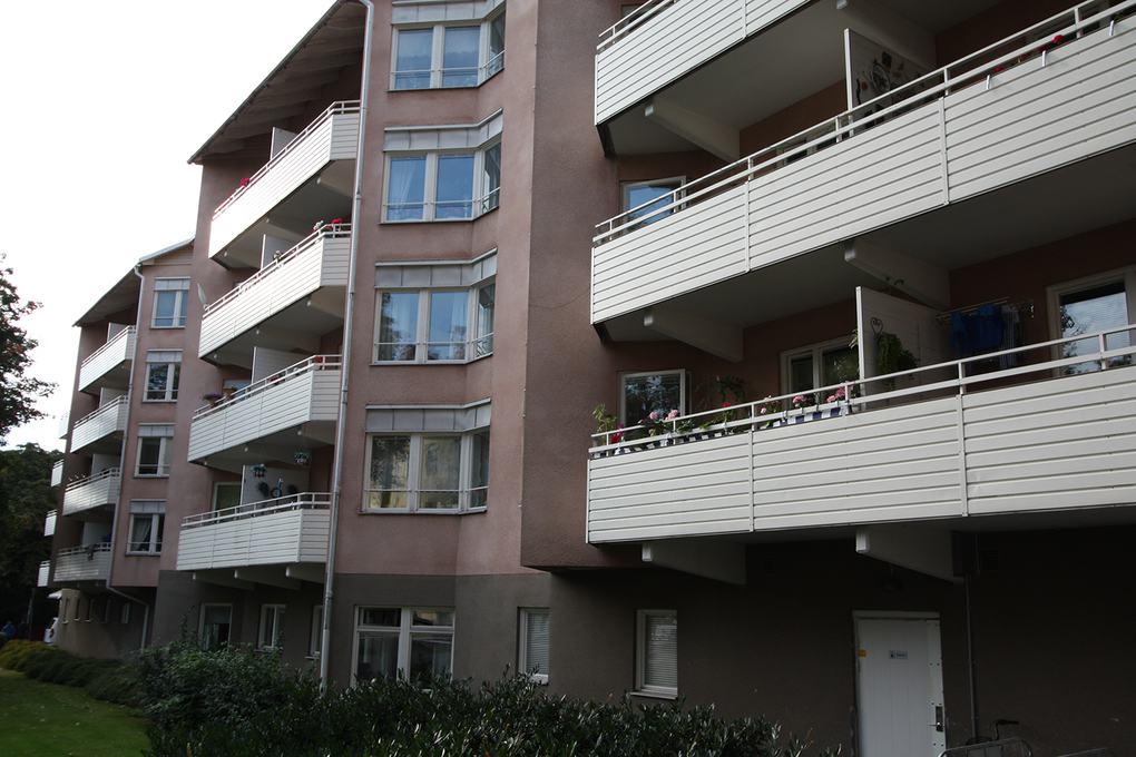 Ett rosa lägenhetshus i fyra våningar med vita balkonger.