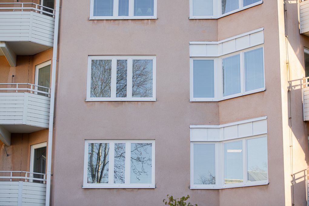 Närbild på rosa flerbostadshus med vita detaljer och balkonger.