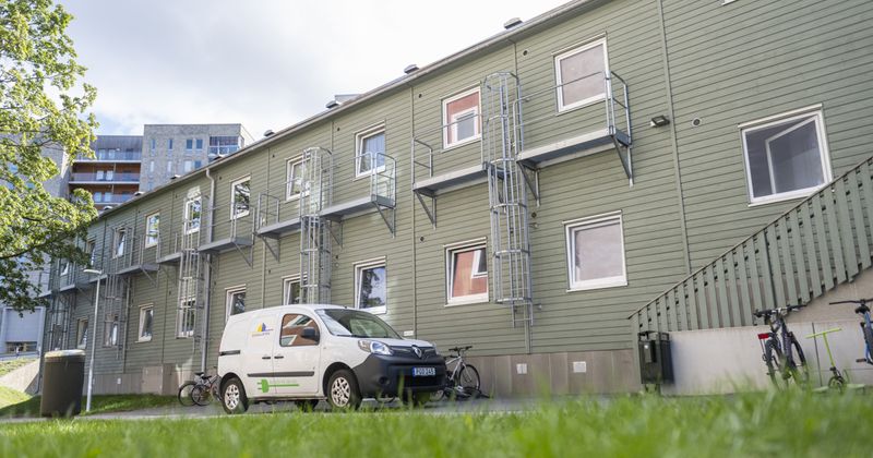 Skogsgrön barack i två våningar, med en vit combibil framför som har Signalistens logga på sig.