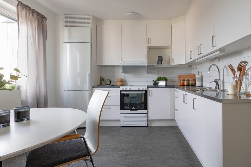 Kök med vita skåpluckor och mörk bänkskiva.