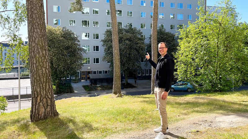 Signalistens projektchef Patrik Törnevik står i sol på en grön gräsmatta och pekar på det nyrenoverade Gunnarbohuset i Bagartorp, Solna. Solen skiner och man ser lite träd och grönska runt honom, huset är i bakgrunden.