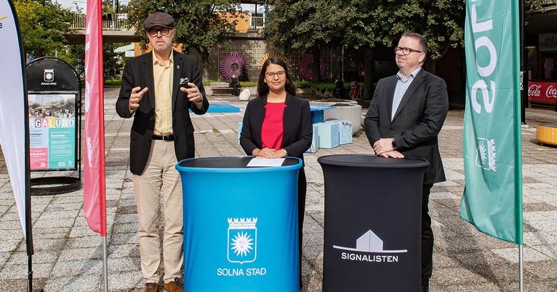 Tre personer står vid två ståbord.