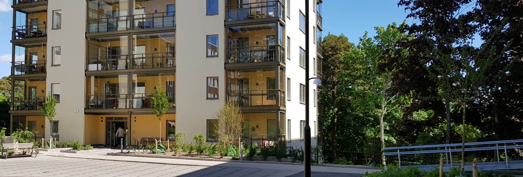 Vitt och gult lägenhetshus med inglasade balkonger.