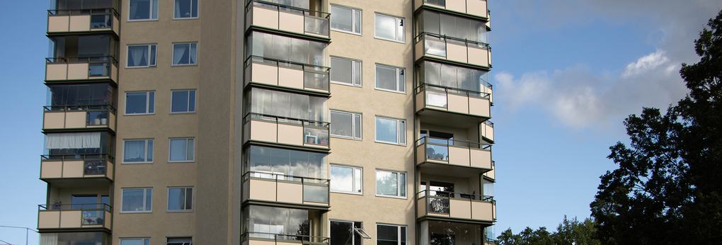 Gult lägenhetshus med balkonger, flera inglasade.
