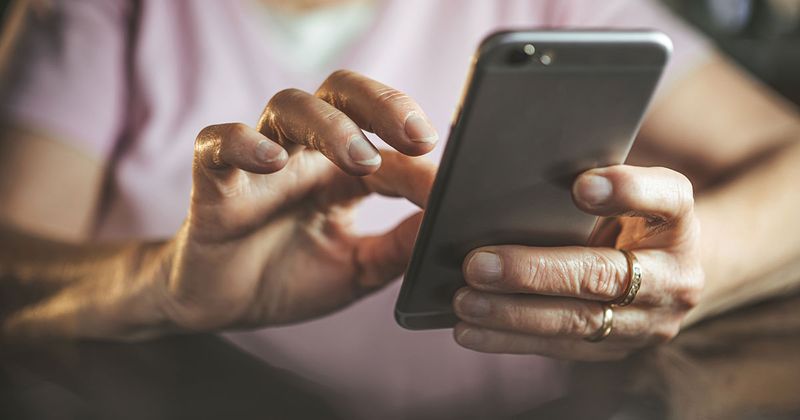 Kvinnas händer som håller i en mobiltelefon