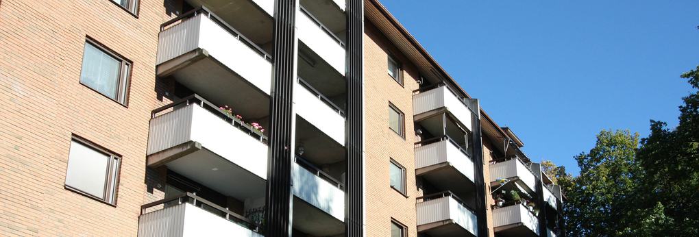 Brunrött lägenhetshus med vita balkonger.
