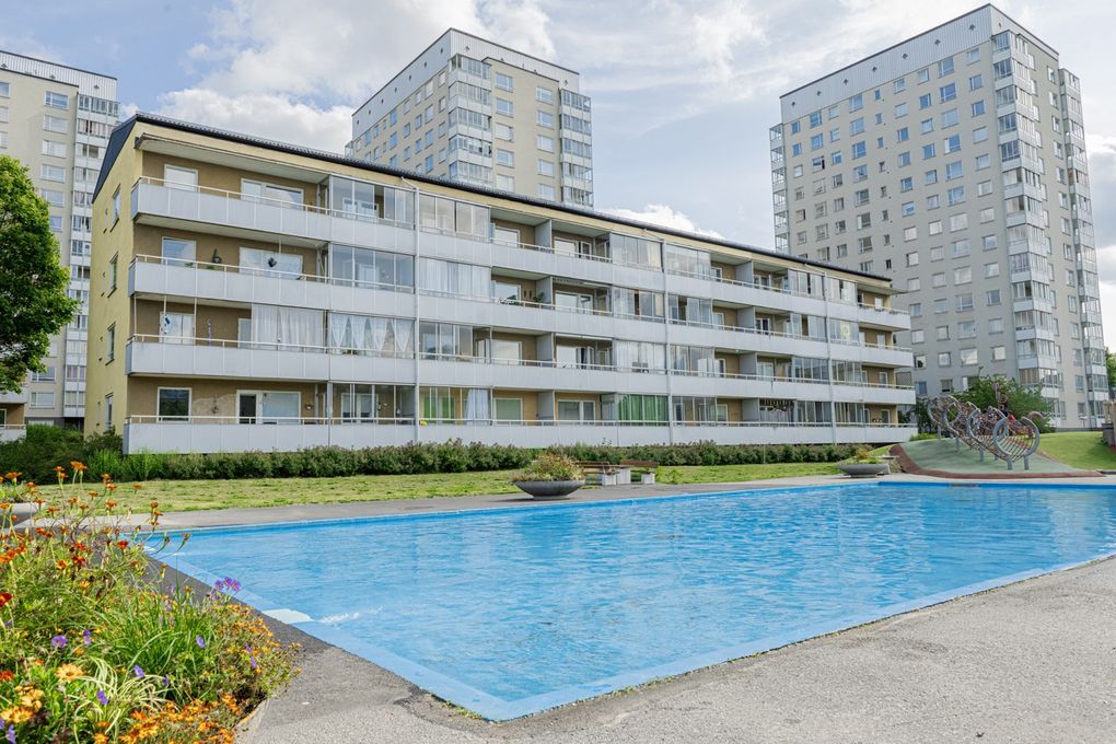 En plaskdamm i förgrunden och låg- och höghus i bakgrunden.