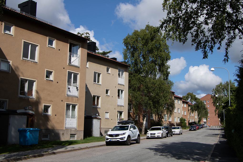Flera lägenhetshus längs en gata, samtliga med tre våningar och i olika nyanser av brunt.