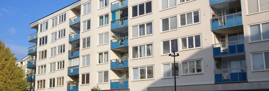 Vitt lägenhetshus med blå balkonger.