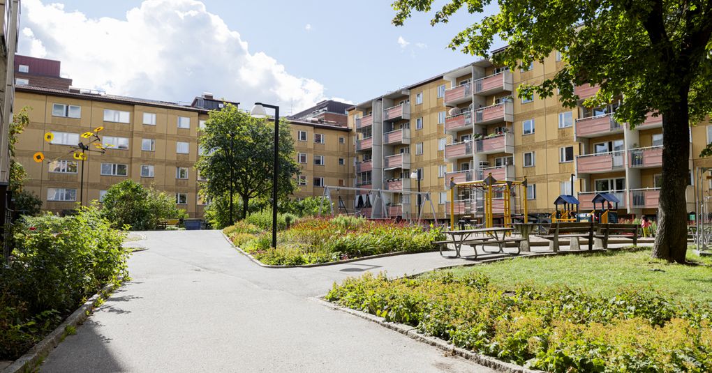 Innergård med gröna ytor och gångvägar, omgivet av gula flerbostadshus.