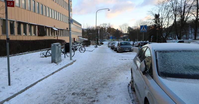 Nyskottad gata utanför ett höghus med orange fasad.