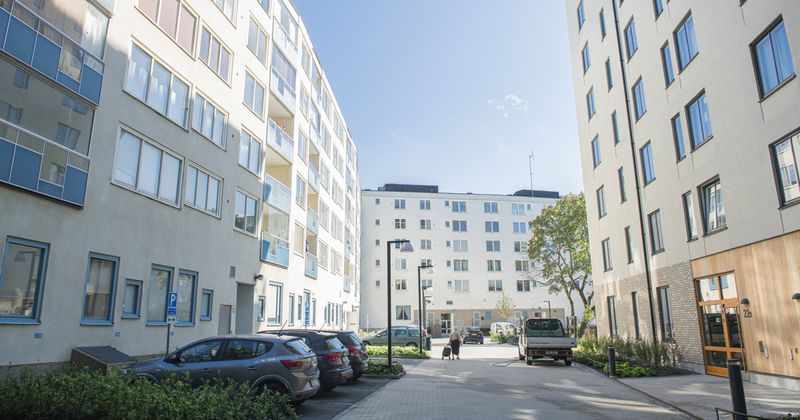 Tre huskroppar i ett u med parkeringsplatser i mitten.