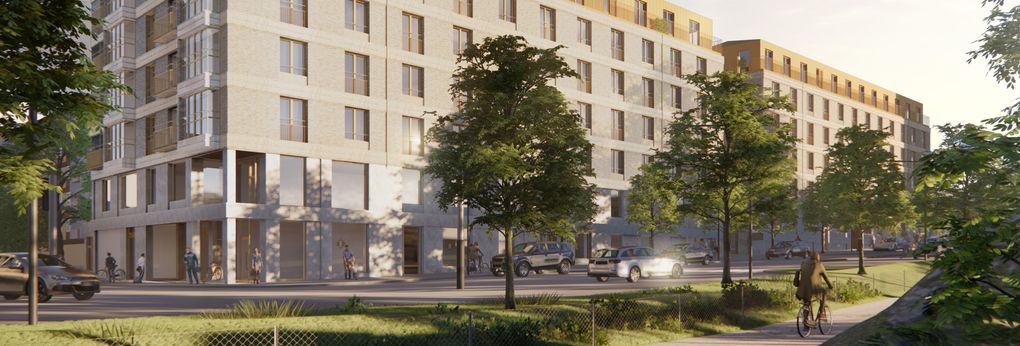 En husfasad i ljusa färger sett snett från gaveln med långsidan längs med en bilväg omringad av grönskande träd och i förgrunden skymtas ryggen av en man cykla på cykelbana parallellt med bilvägen.