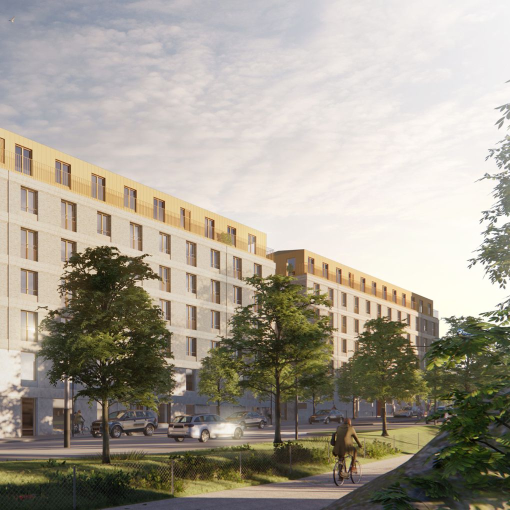 En husfasad i ljusa färger sett snett från gaveln med långsidan längs med en bilväg omringad av grönskande träd och i förgrunden skymtas ryggen av en man cykla på cykelbana parallellt med bilvägen.