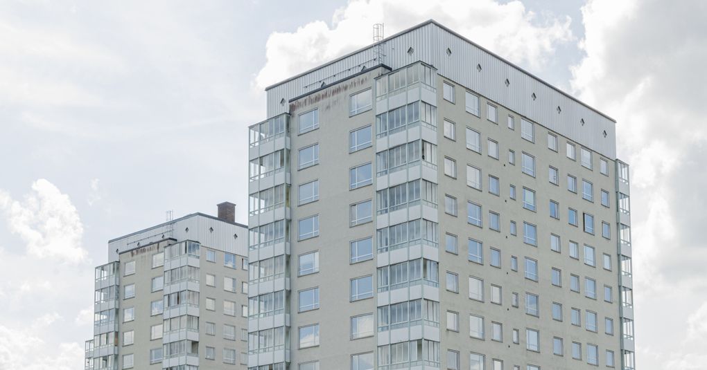 Toppen av två vita höghus mot himmeln.