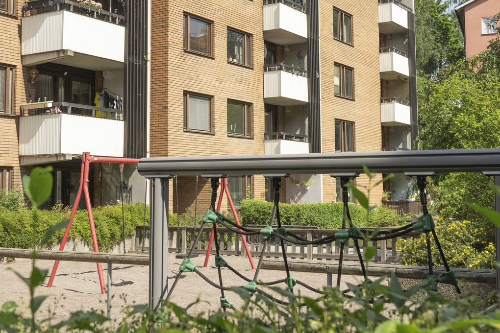 Lekplats på innergård till ett brunt tegelhus.