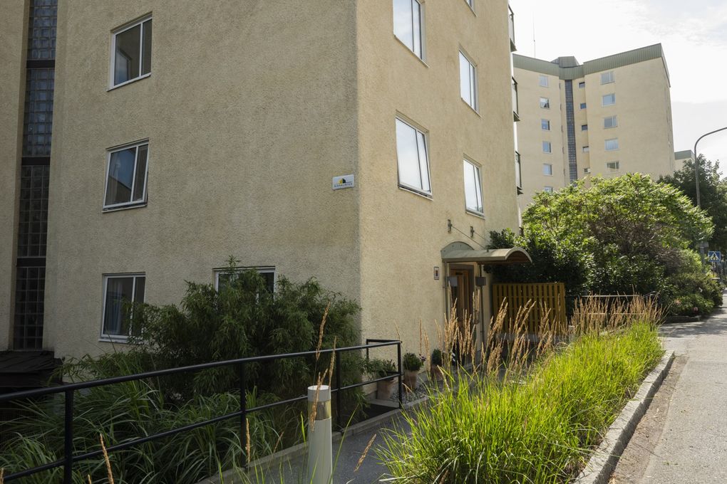 Gångväg som leder till porten till ett ljust höghus med gröna detaljer.