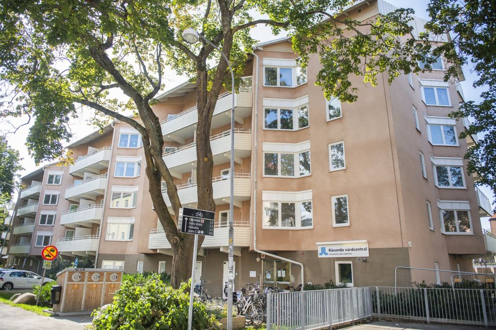 Rosa flerbostadshus med vita balkonger.