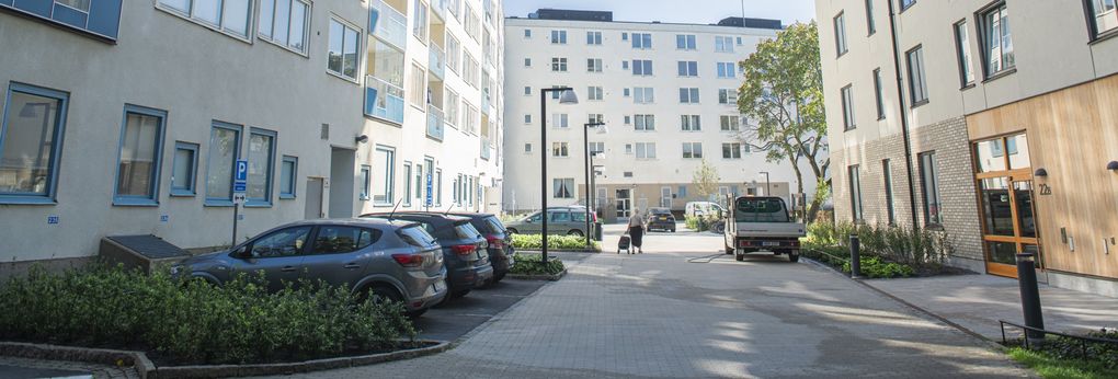 Bilar som står parkerade utanför bostadshus.