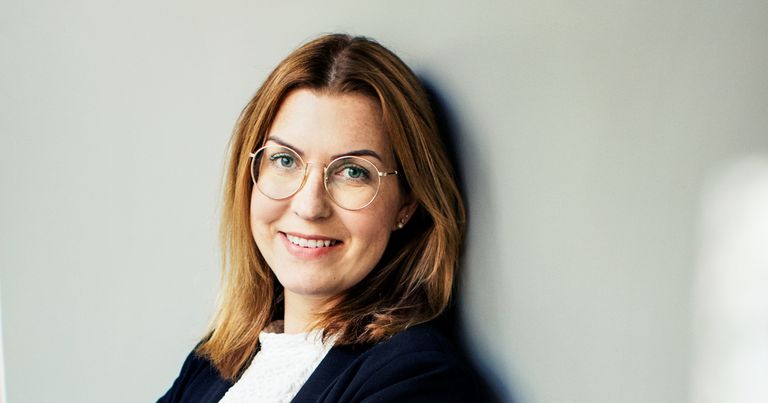 Kvinna med glasögon, kavaj och brunt hår.