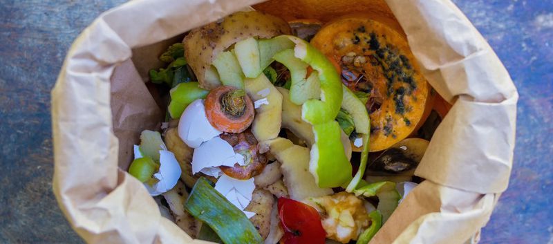Brun papperspåse för matavfall fylld av rester från grönsaker och skal från ägg och frukt.