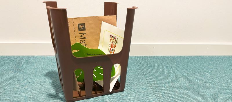 Sorteringskit för matavfall med brun påshållare, en grön slaskskrapa, papperspåse och A5-broschyr om matavfall med mestadels vitt omslag.